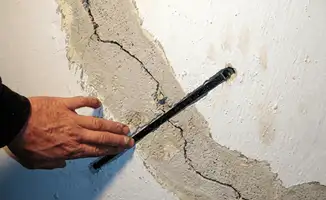 A wall with a large crack is being inspected by a professional in Savannah, GA